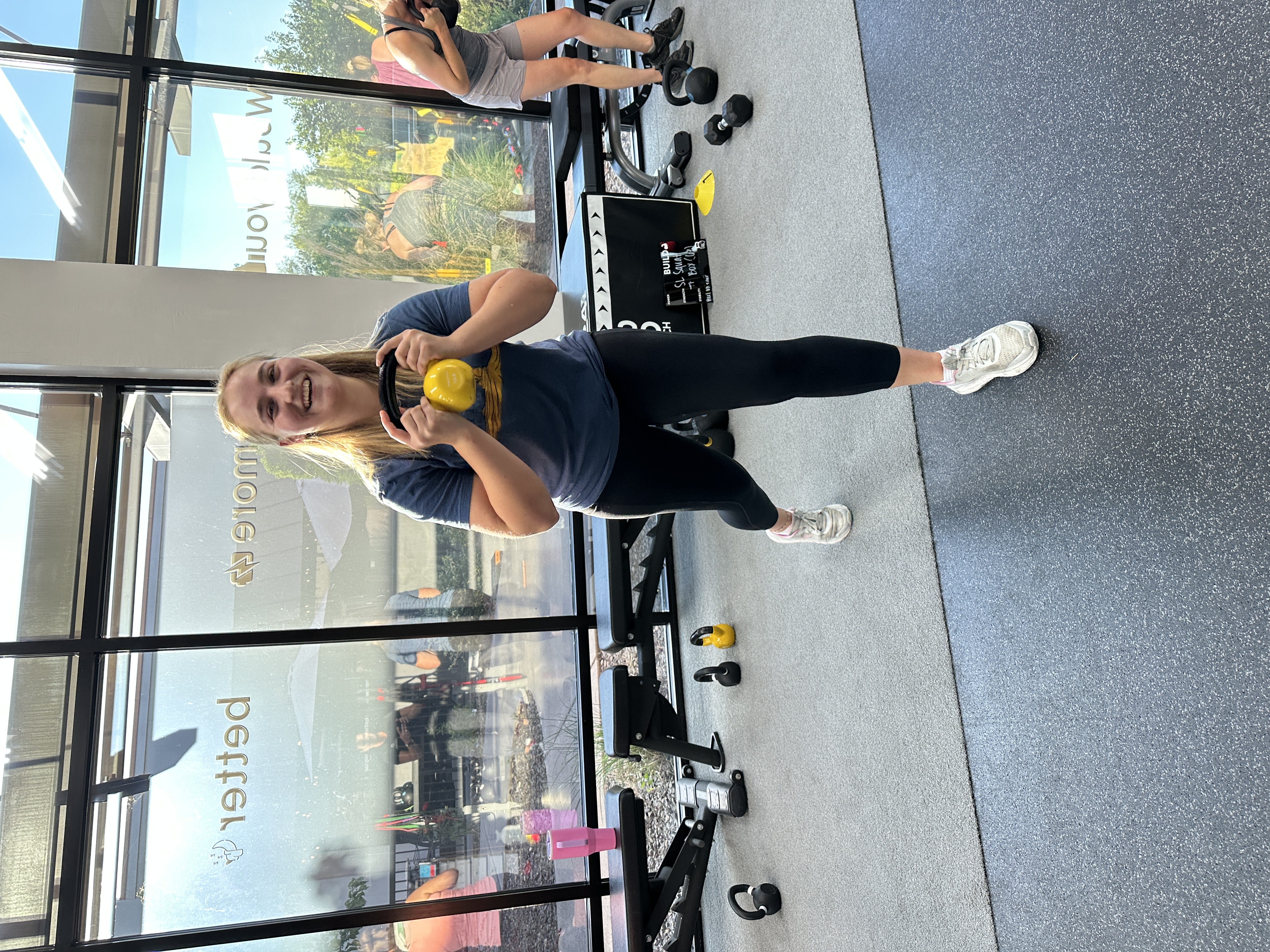 Woman holding a kettlebell in a supportive training environment