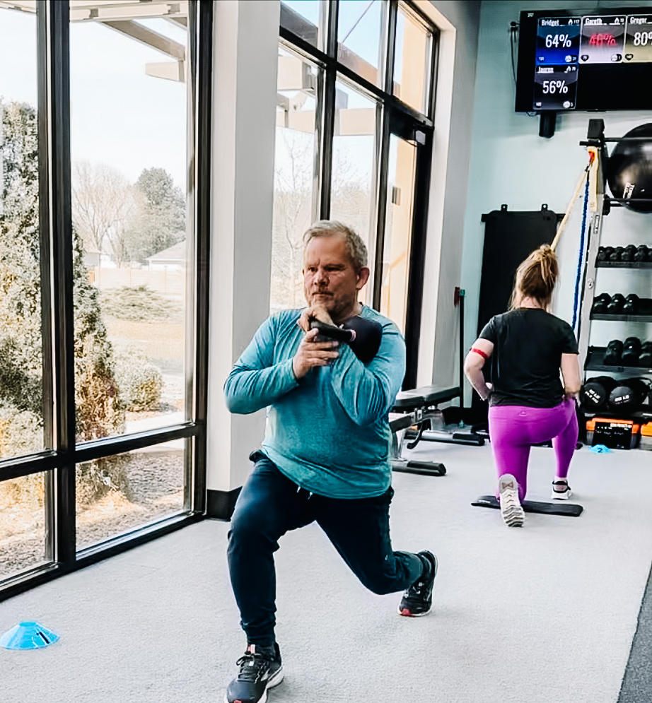 Fit individual performing a rotational kettlebell lunge exercise in a modern gym